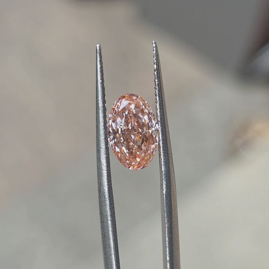 Outdoor sunlight showcases the sparkle of a 2.31ct oval brilliant cut fancy vivid pink lab diamond.