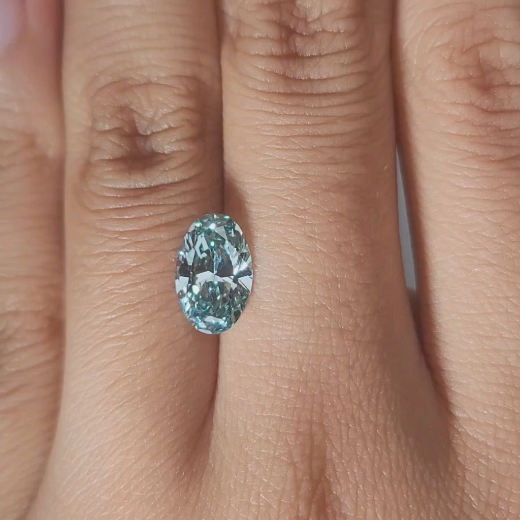 Hand-modeled close-up of 1.762ct blue oval diamond in warm indoor lighting