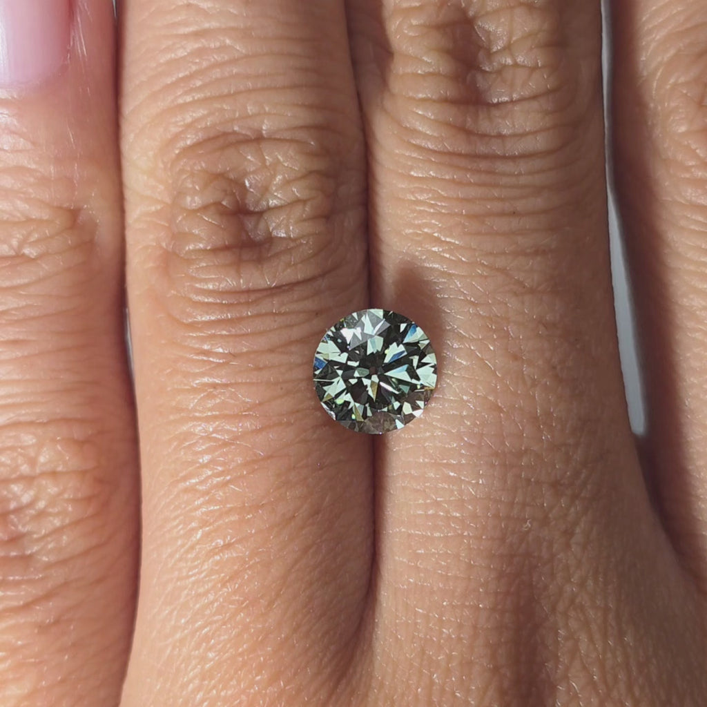 Hand modeling a 1.55ct round old European cut fancy vivid green VVS2 lab diamond in warm indoor light.