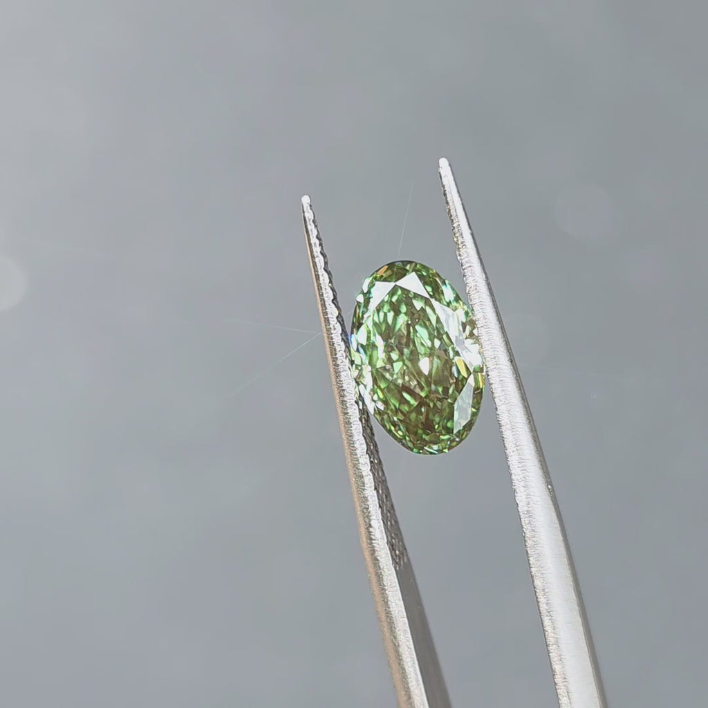 2.24ct oval brilliant cut fancy vivid green VVS1 lab diamond displaying vibrant color in outdoor sunlight.