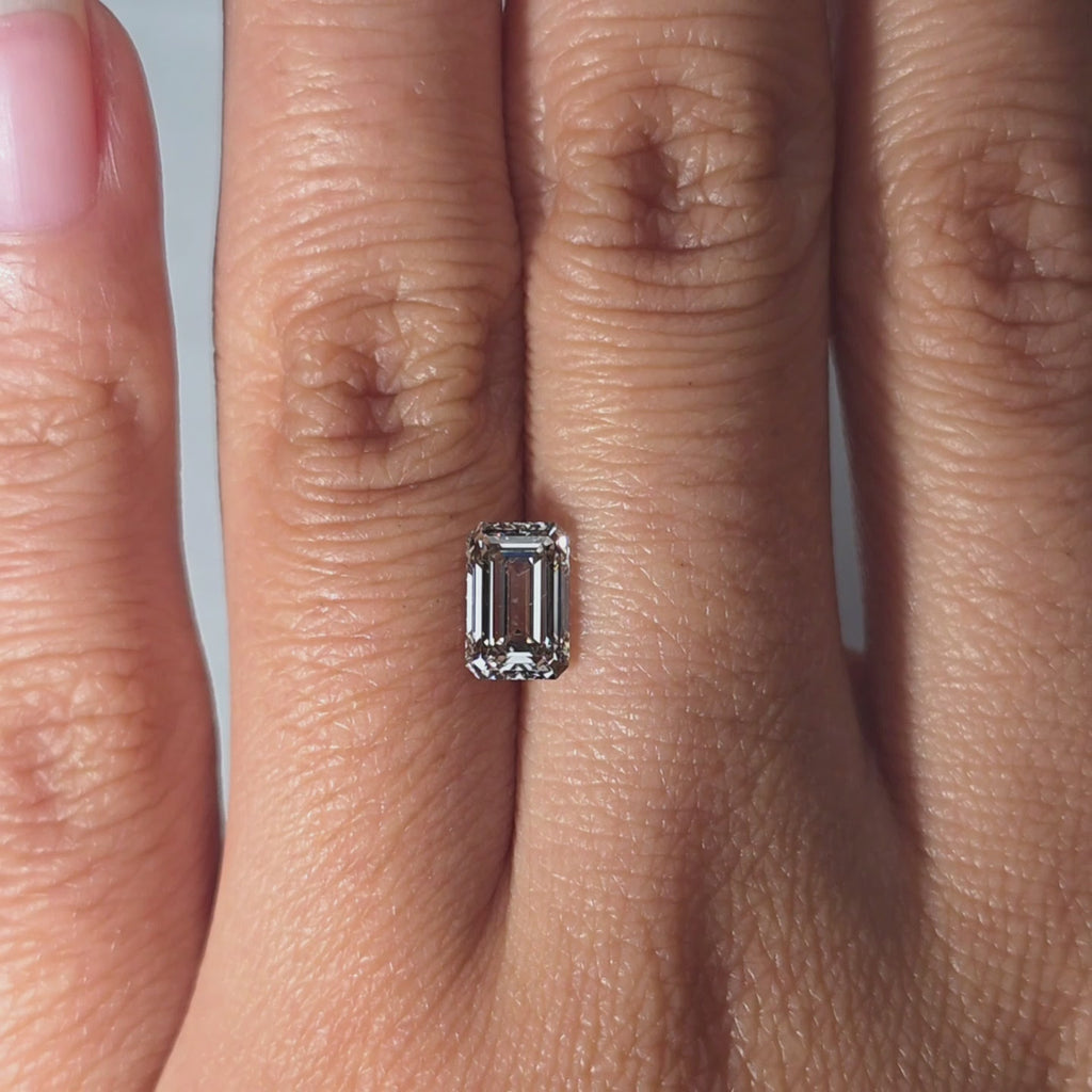 Hand modeling a 1.24ct emerald cut fancy gray VS1 lab diamond in warm indoor light.