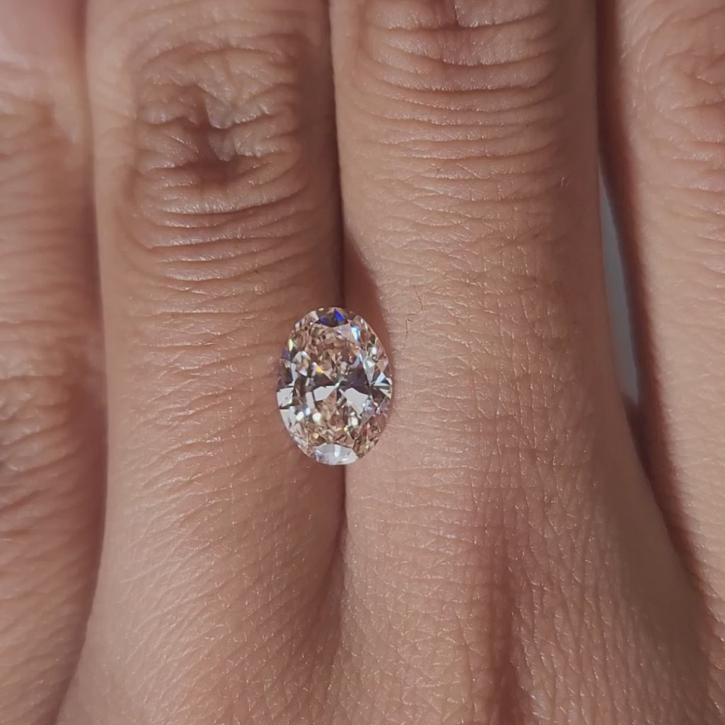 Close-up hand video displaying 1.509ct pink oval diamond in cozy indoor light