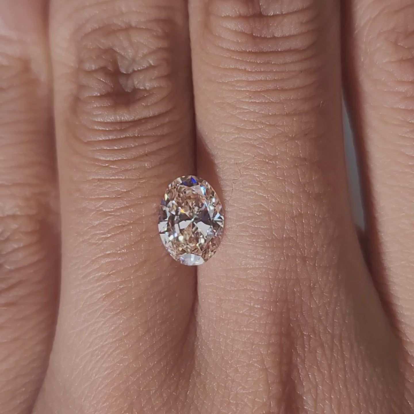 Close-up hand video displaying 1.509ct pink oval diamond in cozy indoor light