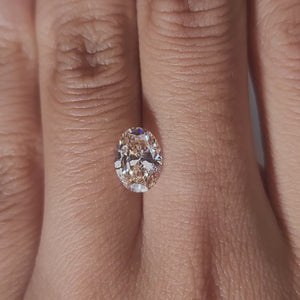 Close-up hand video displaying 1.509ct pink oval diamond in cozy indoor light