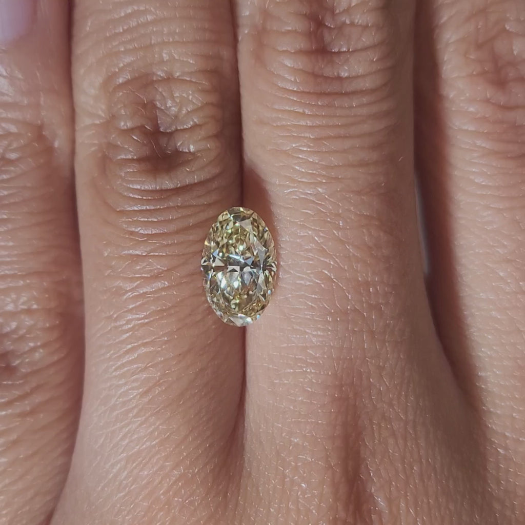 "Hand-modeled video of 1.635ct yellow oval diamond in warm indoor lighting"