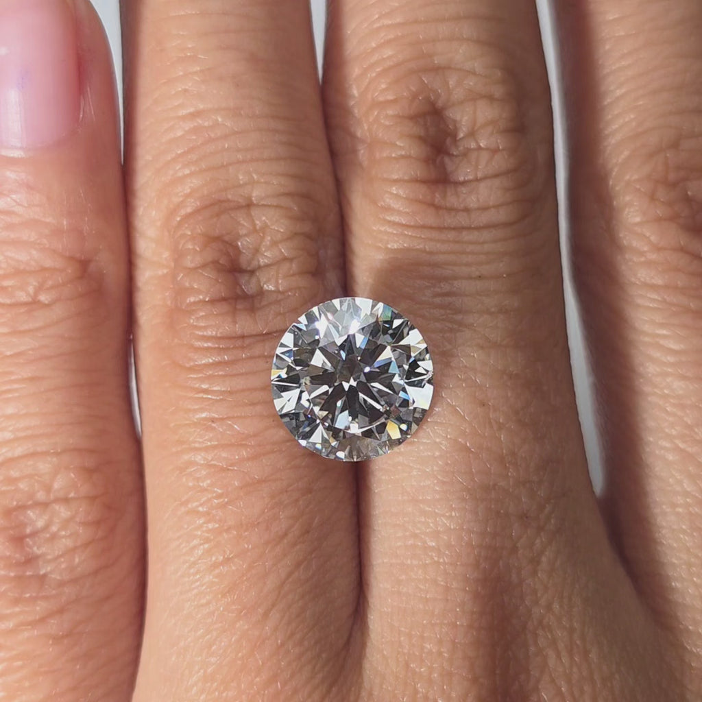 Hand modeling a 5.00ct round brilliant cut F color VS1 lab diamond in warm indoor light.