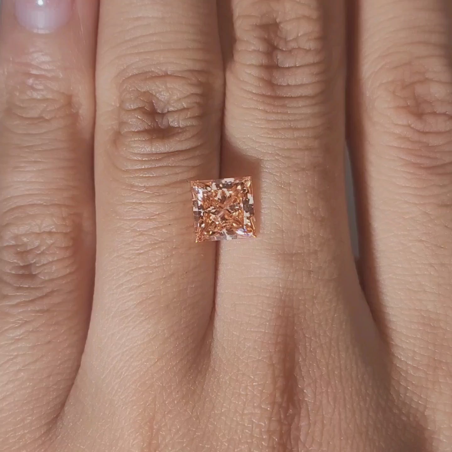 Close-up slow motion of 2.067ct princess cut diamond's brilliant facets under warm lighting