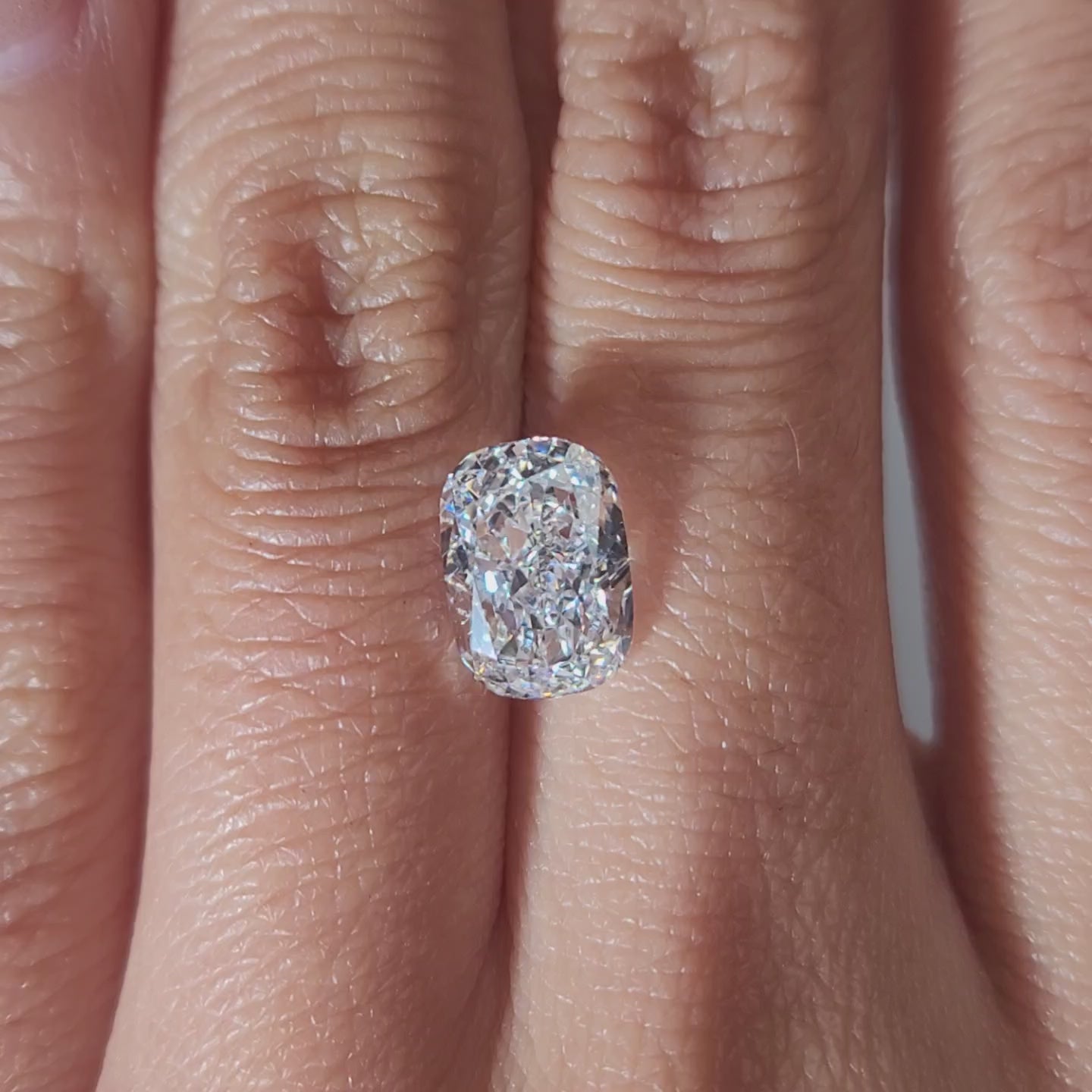 "Hand-modeled video of 2.600ct cushion diamond in warm indoor lighting"