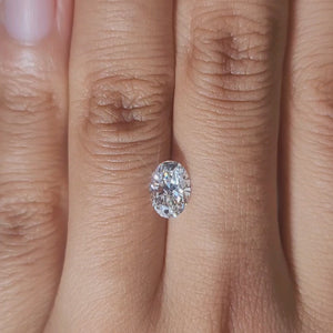 Hand-modeled close-up of 1.02ct oval lab diamond in warm indoor lighting