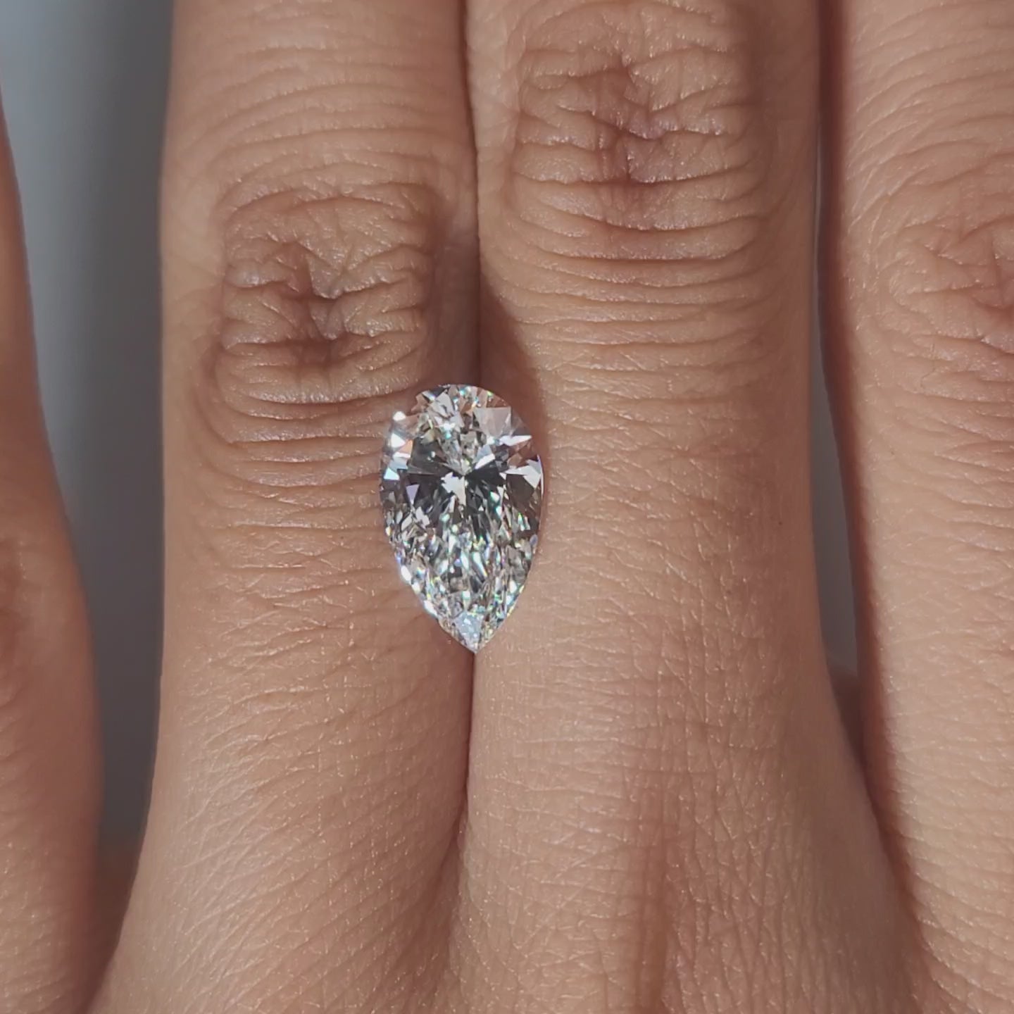 Hand-display video showing 2.50ct pear diamond in warm home lighting