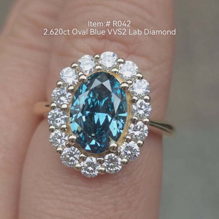 2.62ct oval cut blue lab grown diamond engagement ring with diamond halo in two-tone gold setting, shown on hand in natural light 
