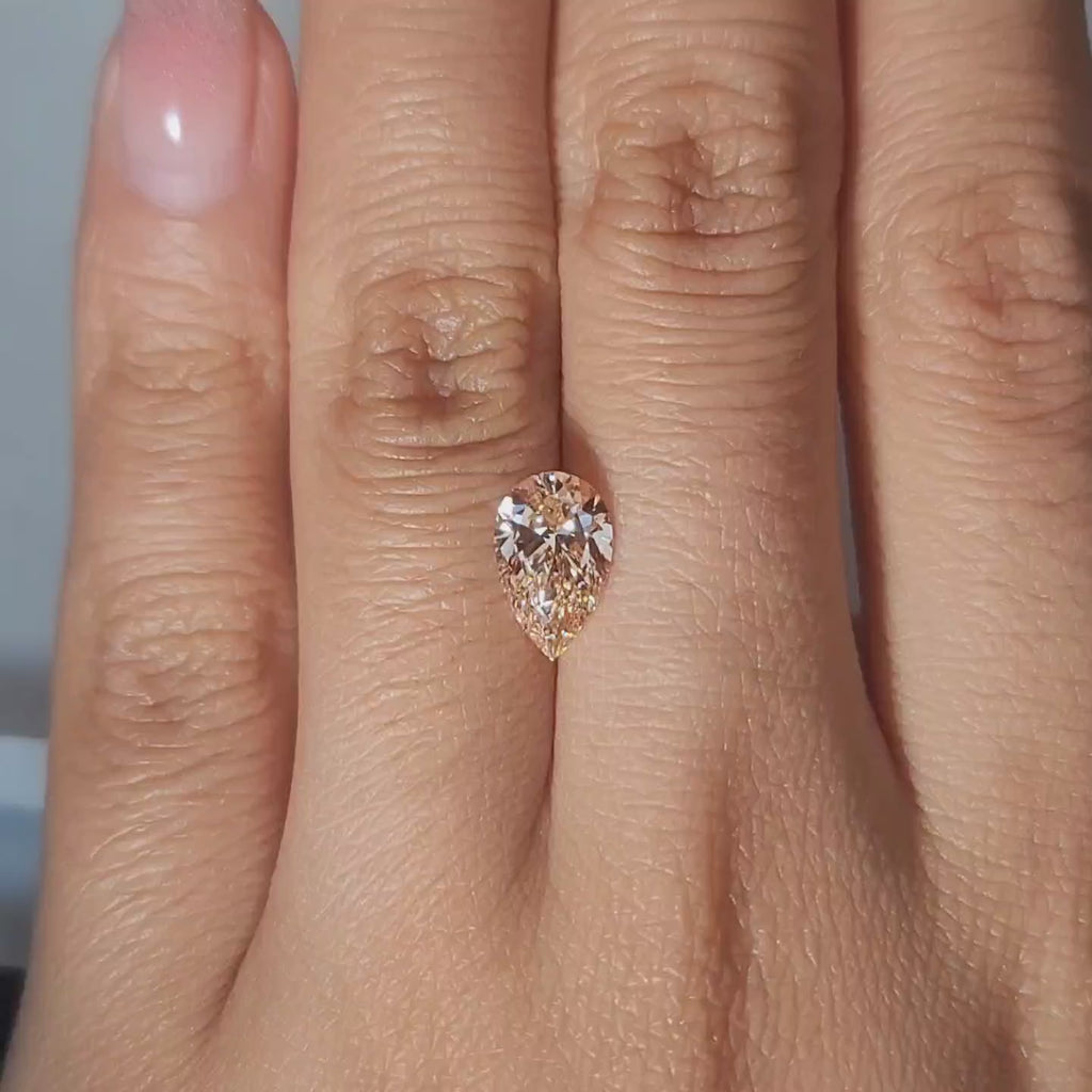 1.50ct Pear orange diamond showcased in soft candlelight glow