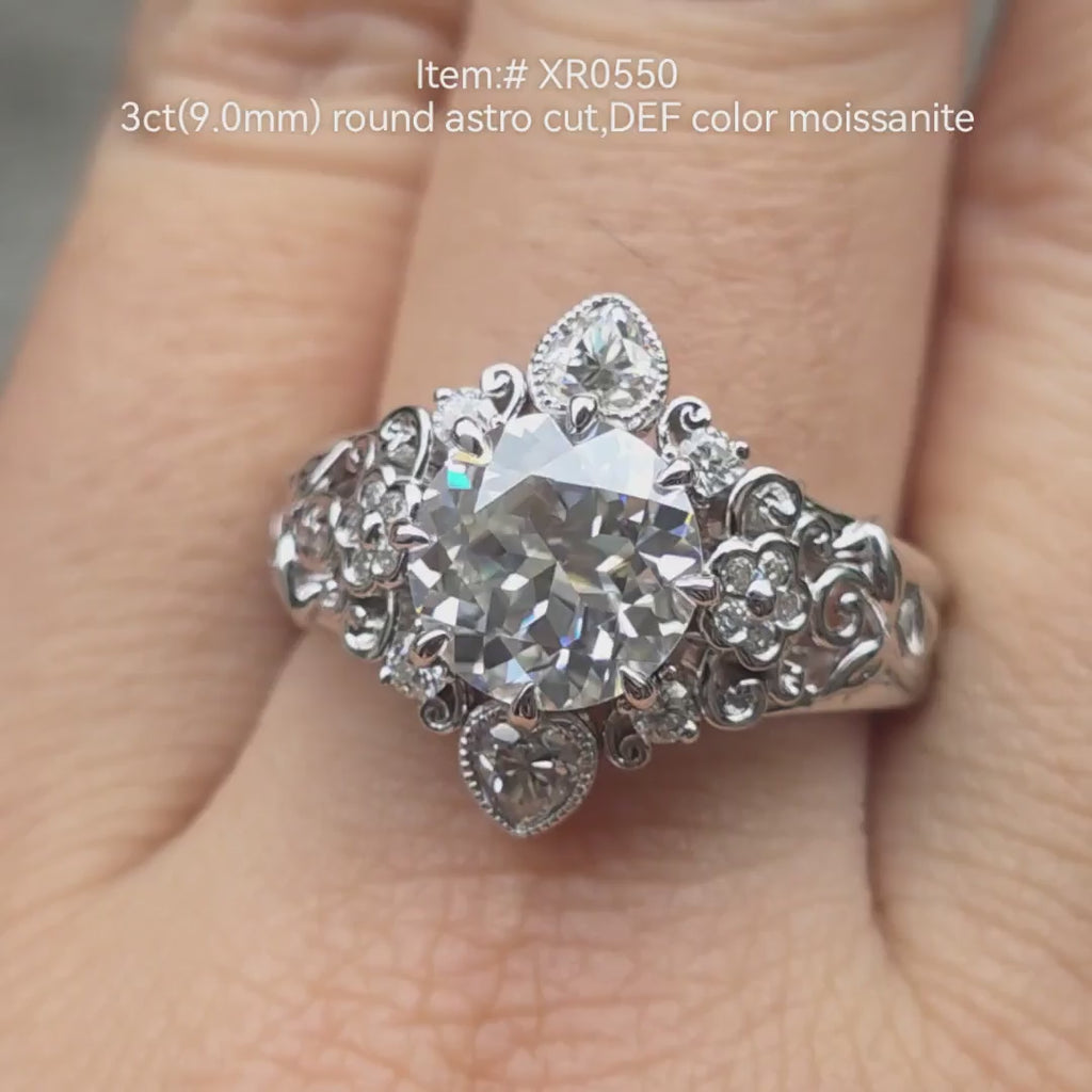 3ct round Astro Cut colorless moissanite engagement ring in vintage floral filigree setting with milgrain accents, shown on hand in natural light 