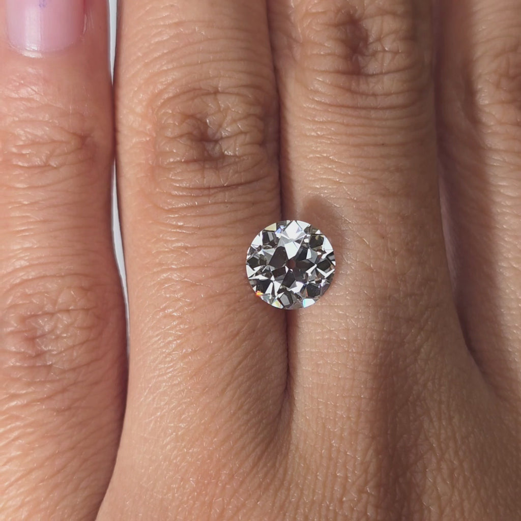 A 2.10ct round European cut lab diamond held in hand, warm indoor lighting.