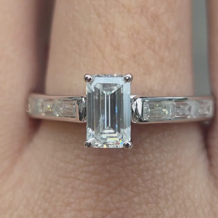 Custom emerald moissanite engagement ring under outdoor ligjting